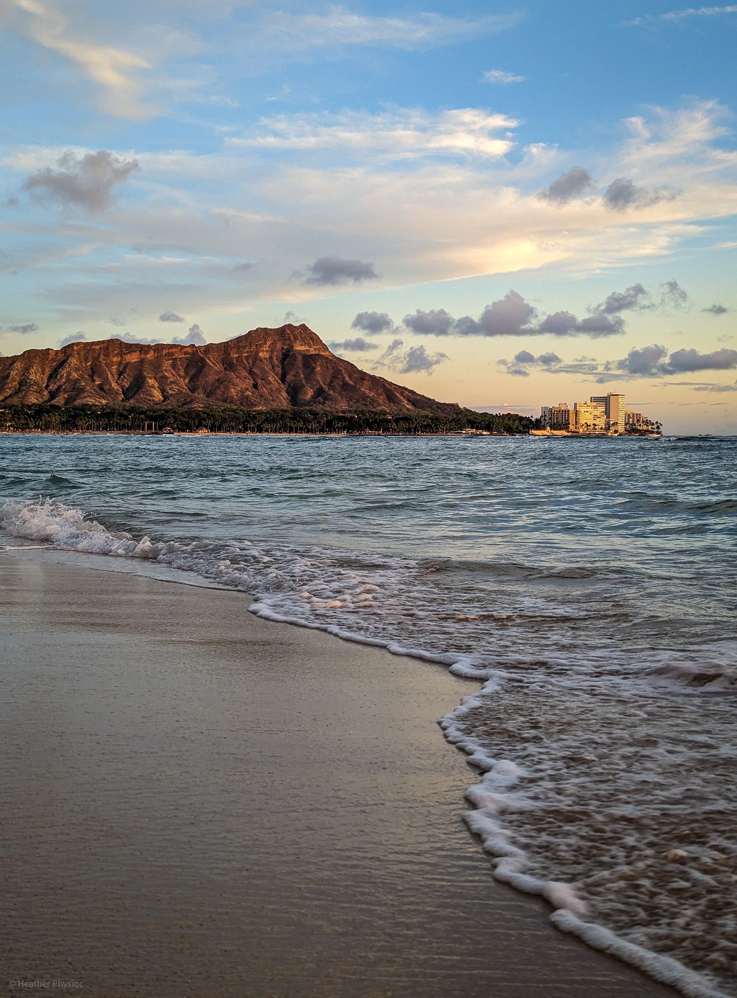 Warm Waikiki beach golden hour light cast on Diamond Head Crater