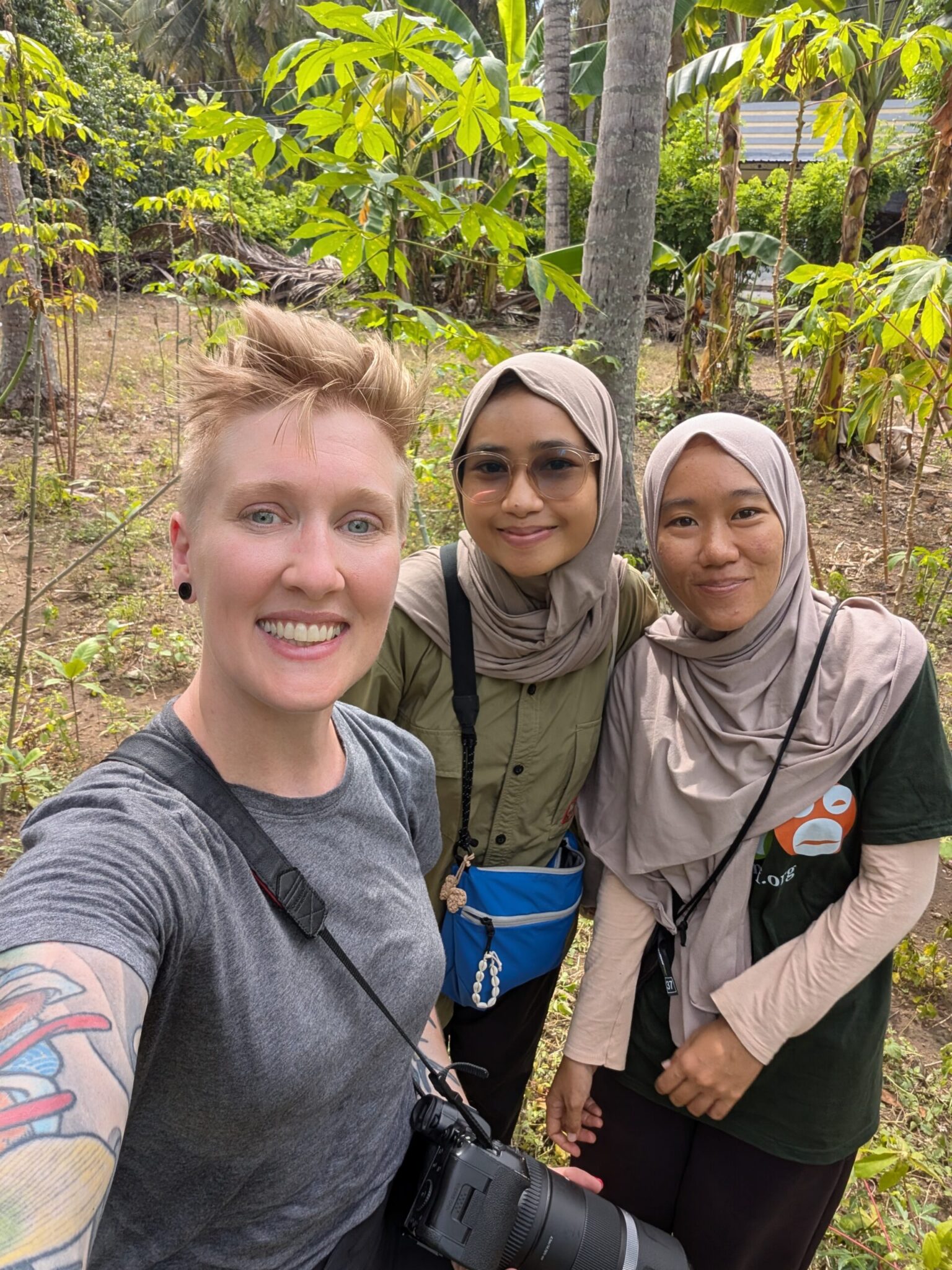 Conservation photojournalist Heather Physioc in a selfie with two young conservation staffers from FNPF on Nusa Penida, staking out a natural cavity nest of a Bali Starling in a coconut palm grove