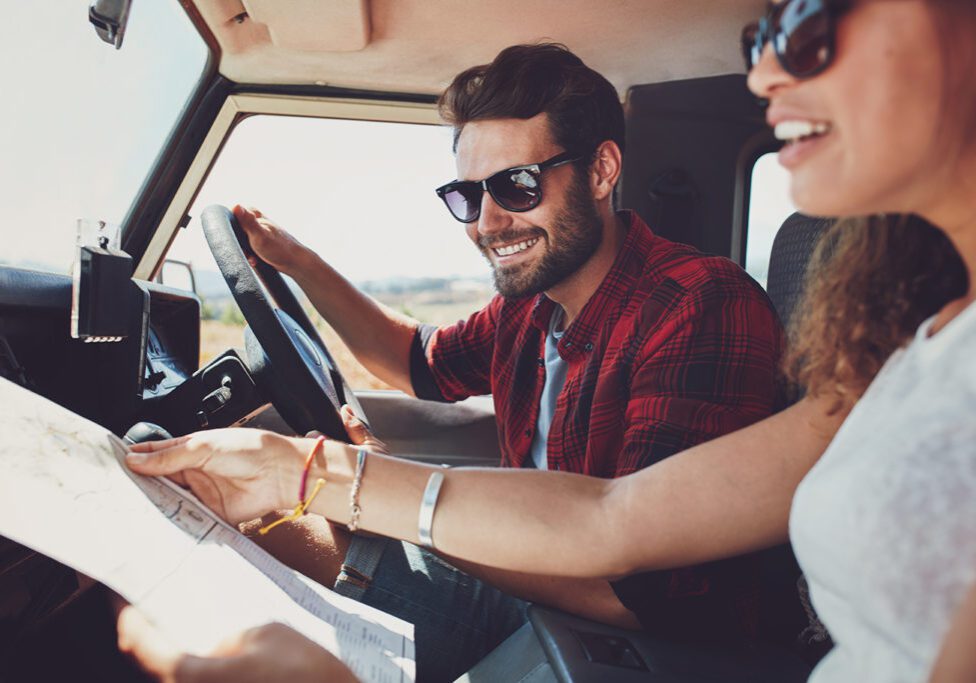 Couple Planning Road Trip with Map in Rental Car